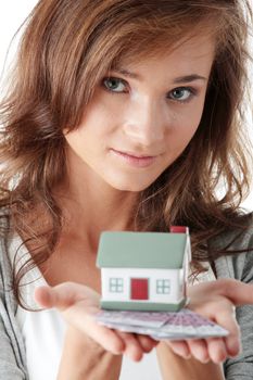 Beautiful young woman holding euros bills and house model over white