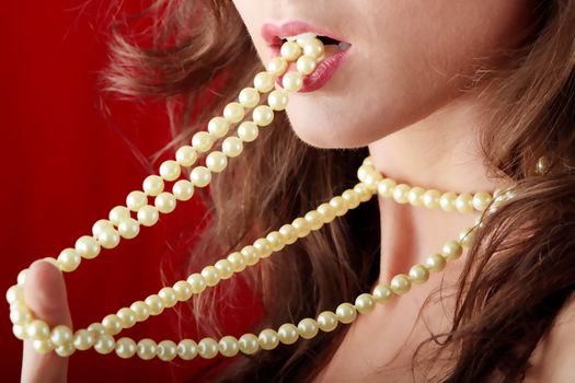 Sexy young woman with a pearl necklace over red background