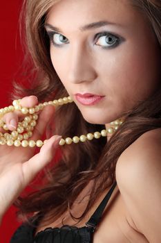 Sexy young woman with a pearl necklace over red background
