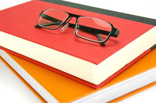 Reading glasses and books isolated against a white background