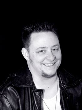 a man in a leather jacket smiling in black and white.