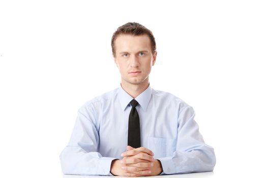 Young businessman sitting behind the desk isolated