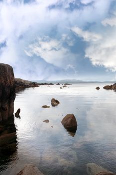 scenic view in kerry ireland of rocks and sea with mountains against a beautiful blue cloudy sky