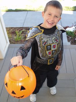 Little boy in a knight outfit trick or treating at the door.