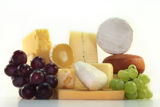 different varieties of cheese with fresh bright and dark grapes