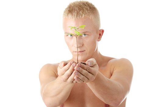 Muscular man holding small plant and soil in his hands. Isolated on white in studio.