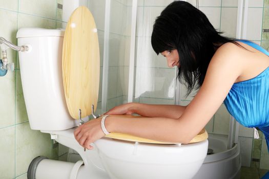 Young caucasian woman in toilet - pregnant,drunk or illness concept