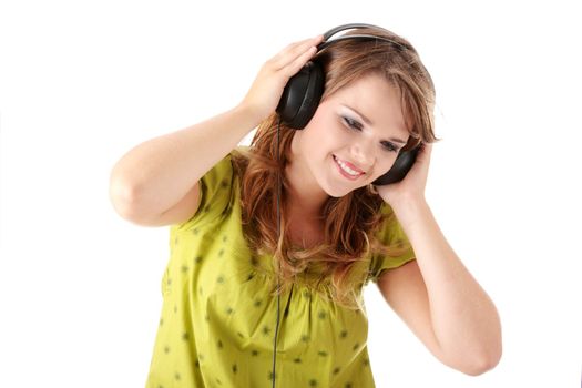 Beautiful teenage girl in a green dress listening to music with big headphones, isolated on white