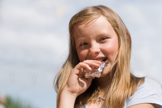 The girl with chocolate rejoices to a sunny day on summer vacations