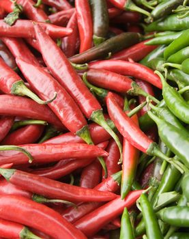 Red and green chilli peppers on market stall.