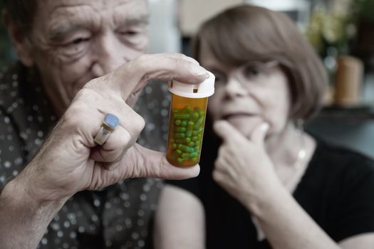 Senior couple at home with prescription bottle, focus