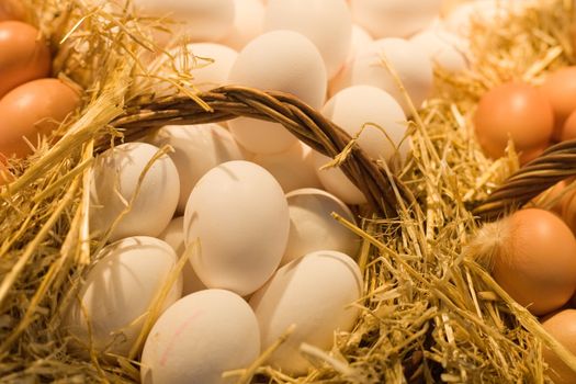 Fresh white and brown eggs in straw baskets.