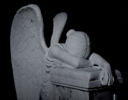 Cemetary headstone of a winged angel weeping over the dead.