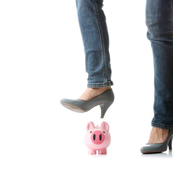 Young woman about to smash piggy bank with her legto get at savings