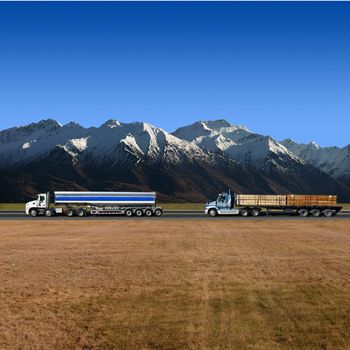 Two Trucks on Highway with Mountains