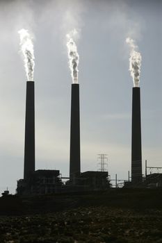 three smoking chimneys of a power plant