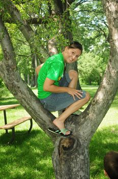 happy caucasian young woman sitting in a tree