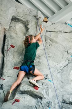 teen ringing the bell at the top of an artificial climbing wall