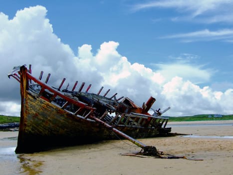 Shipwreck on Bunbeg Beach, Co. Donegal in Ireland with cloudy sky in the background.