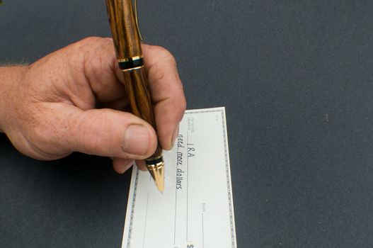 male hand writing check to IRA for more dollars  needed