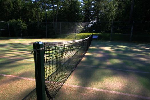View of a tennis net on grass court as sun sets