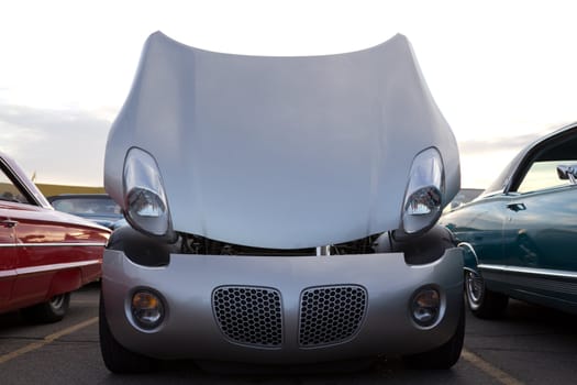 A beautiful sports car with its hood open and headlights looking down