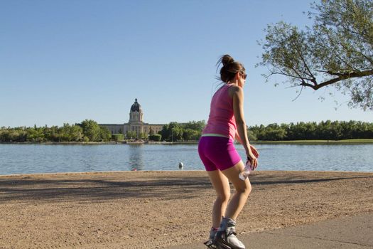 A young woman rollerblading by Wascana Lake on a beautiful afternoon in Regina, Canada