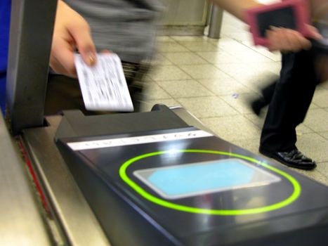 a woman inserting the ticket in hurry at the train gate in the morning rush hours in japan          