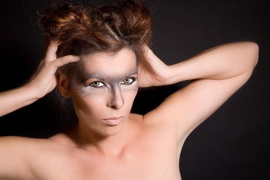 Beautiful woman with wolf eyes and intense look on black background
