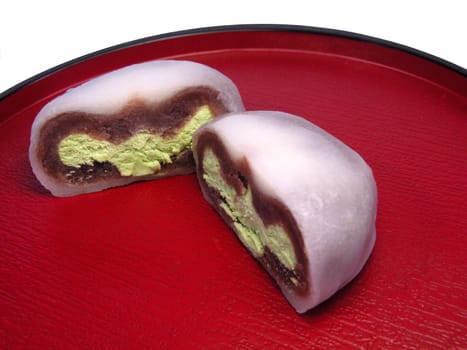 Japanese cake,specific for tea ceremony on a red wooden plate.          