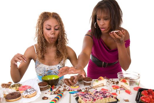 Two girls trying to stuff as much sweets into their mouth as they can