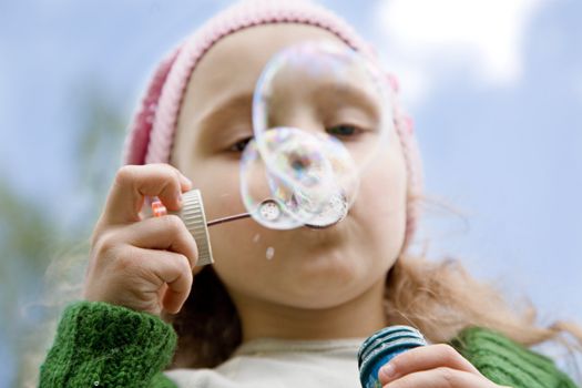 The little girl starts up soap bubbles close up
