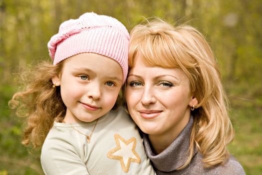 The beautiful little girl in a pink cap with smiling mum with light hair
