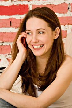 The smiling girl talks by a mobile phone
