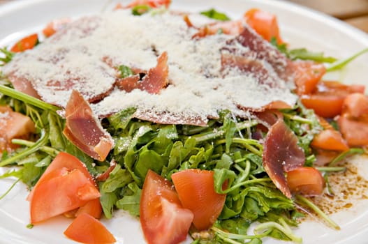 Salad with meat, tomatoes and parmesan on a white plate
