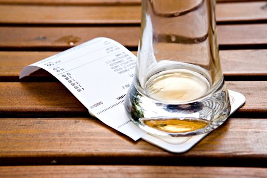 Empty mug from under beer on the check for a table in cafe
