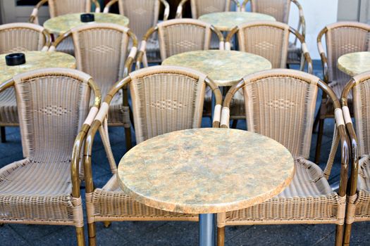 Empty wicker chairs with little tables in a sunny day
