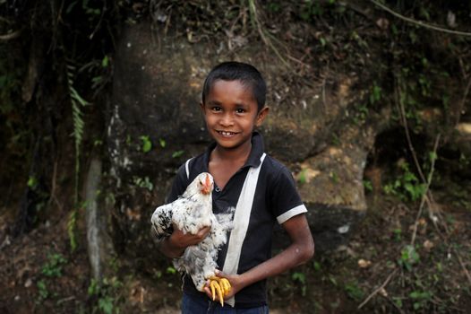 Neluwa, Sri Lanka - January 27, 2011: Sri Lankan boy from small sri lankan village carrying  chicken in his hands and looking to the camera