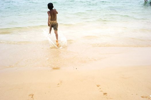 Hikkaduwa, Sri Lanka - February 04, 2011: Sri Lankan boy running on the beach to the ocean.