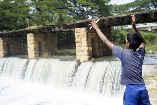 Buttala, Sri Lanka - February 14, 2011: Sri Lankan boy catching a fish near the waterfall.