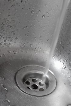 Metallic Kitchen sink with pouring water shot from low angle