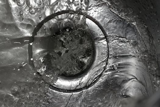 Metallic Kitchen sink swirly water flow and drops shot from above