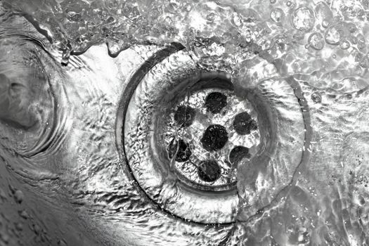 Metallic Kitchen sink swirly water flow and drops shot from above