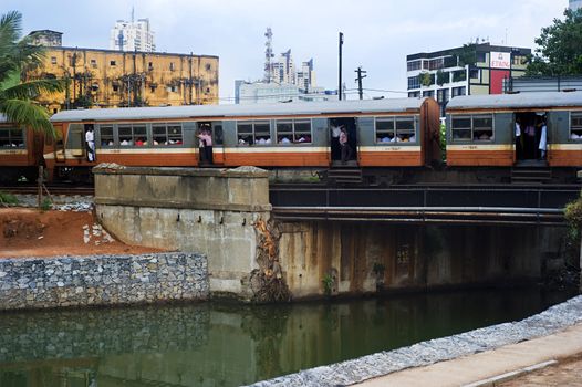 Colombo, Sri Lanka - Feb 22, 2011:  Sri Lankan train passing across the river in Colombo. In Sri Lanka, trains are a cheap, safe and enjoyable way to get around.  Trains link the major cities and have several classes