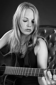 Photo of a beautiful blond female playing an acoustic guitar.