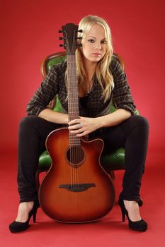 Photo of a young blond female holding a acoustic guitar.