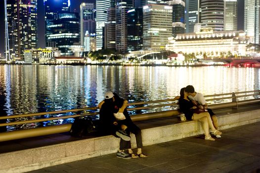 Singapore, Republic of Singapore - May 02, 2011: Teenage couples kissing on embankment of Singapore