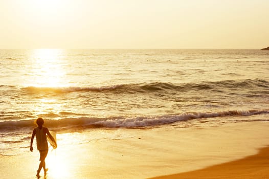 Surfer on the ocean beach at sunset in Hikkaduwa, Sri Lanka