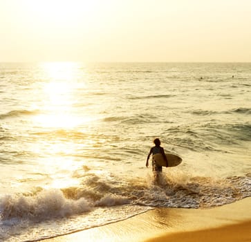 Surfer on the ocean beach at sunset in Hikkaduwa, Sri Lanka