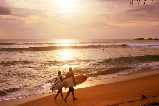 Sri Lanka, Hikkaduwa - March 3, 2011: Couple of surfers walks along the beach in Hikkaduva - is the second best surf paradise in Sri Lanka